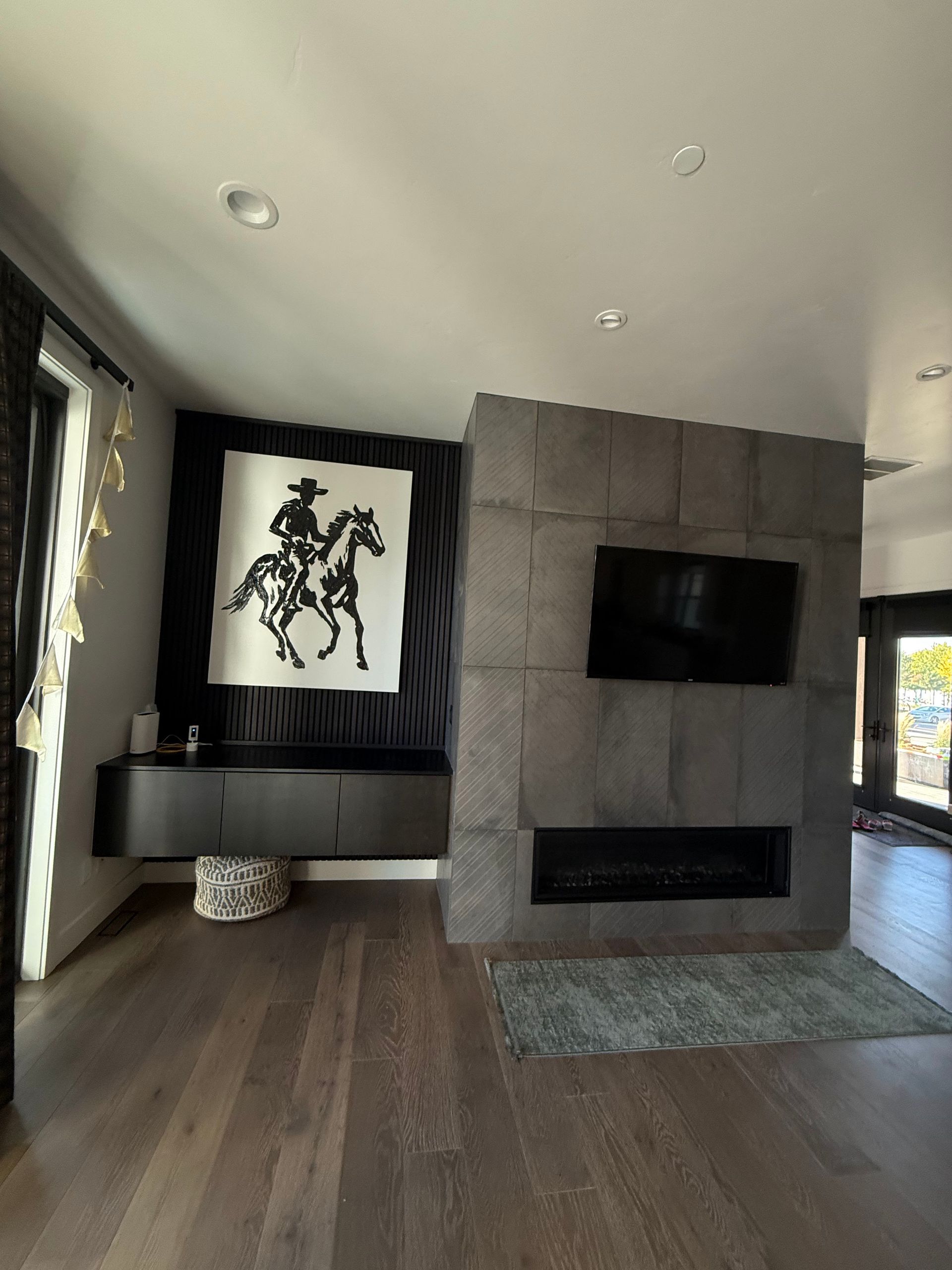 Living room with dark wood floors, gray stone fireplace, and cowboy art.