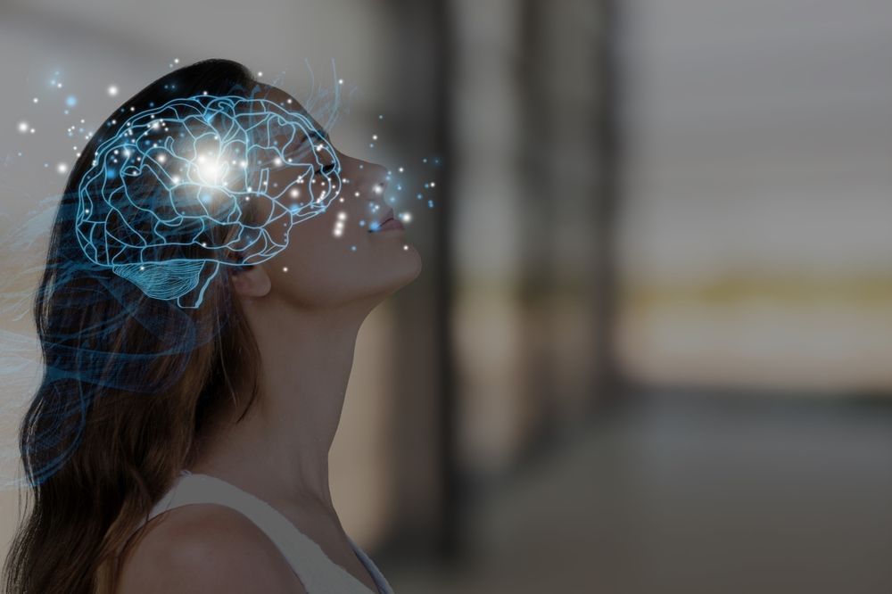 Woman with illuminated brain overlay, looking upward. Blue light emanates from the brain, suggesting thought.