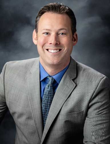 A man in a suit and tie is smiling for the camera.
