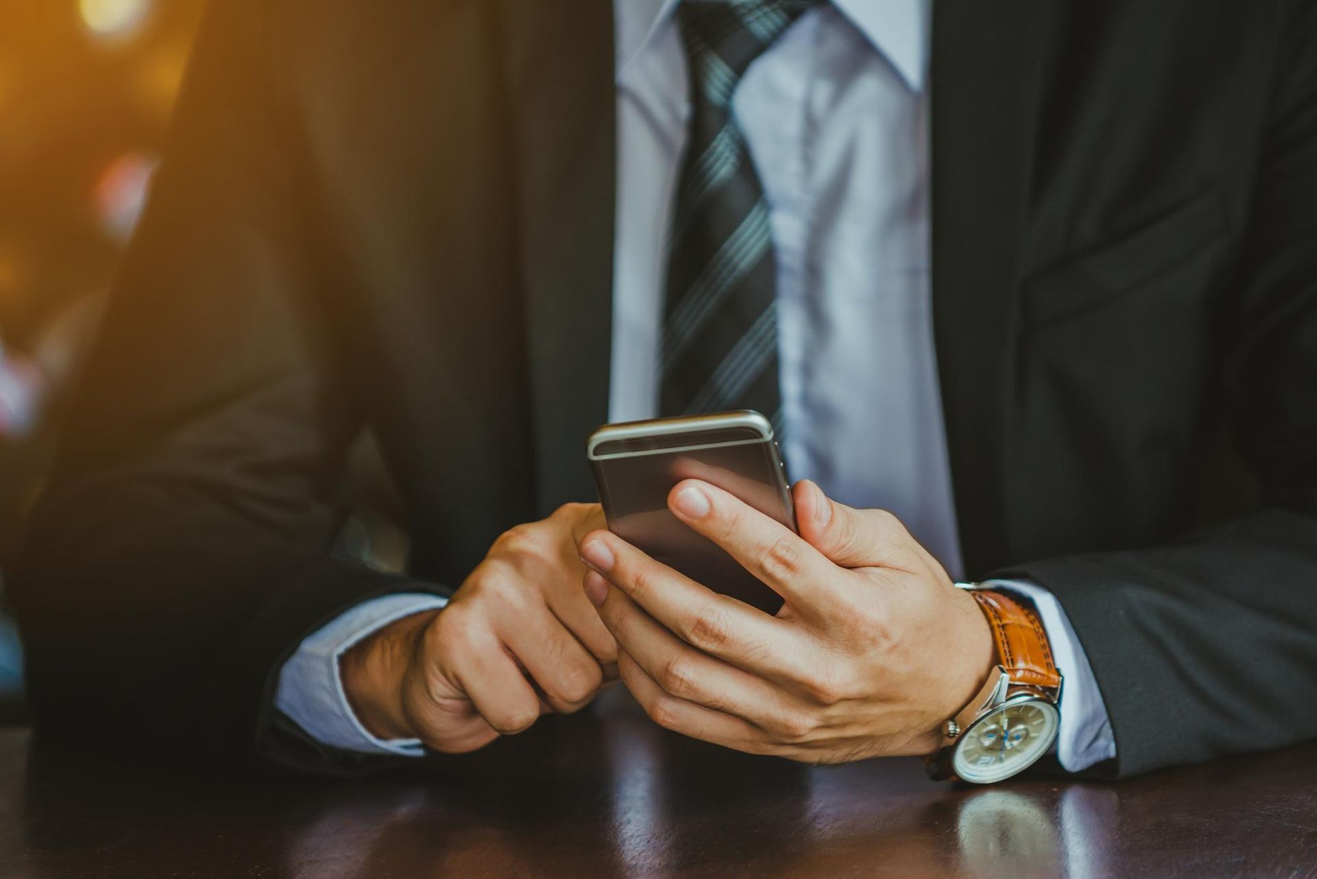 A man in a suit and tie is using a cell phone.