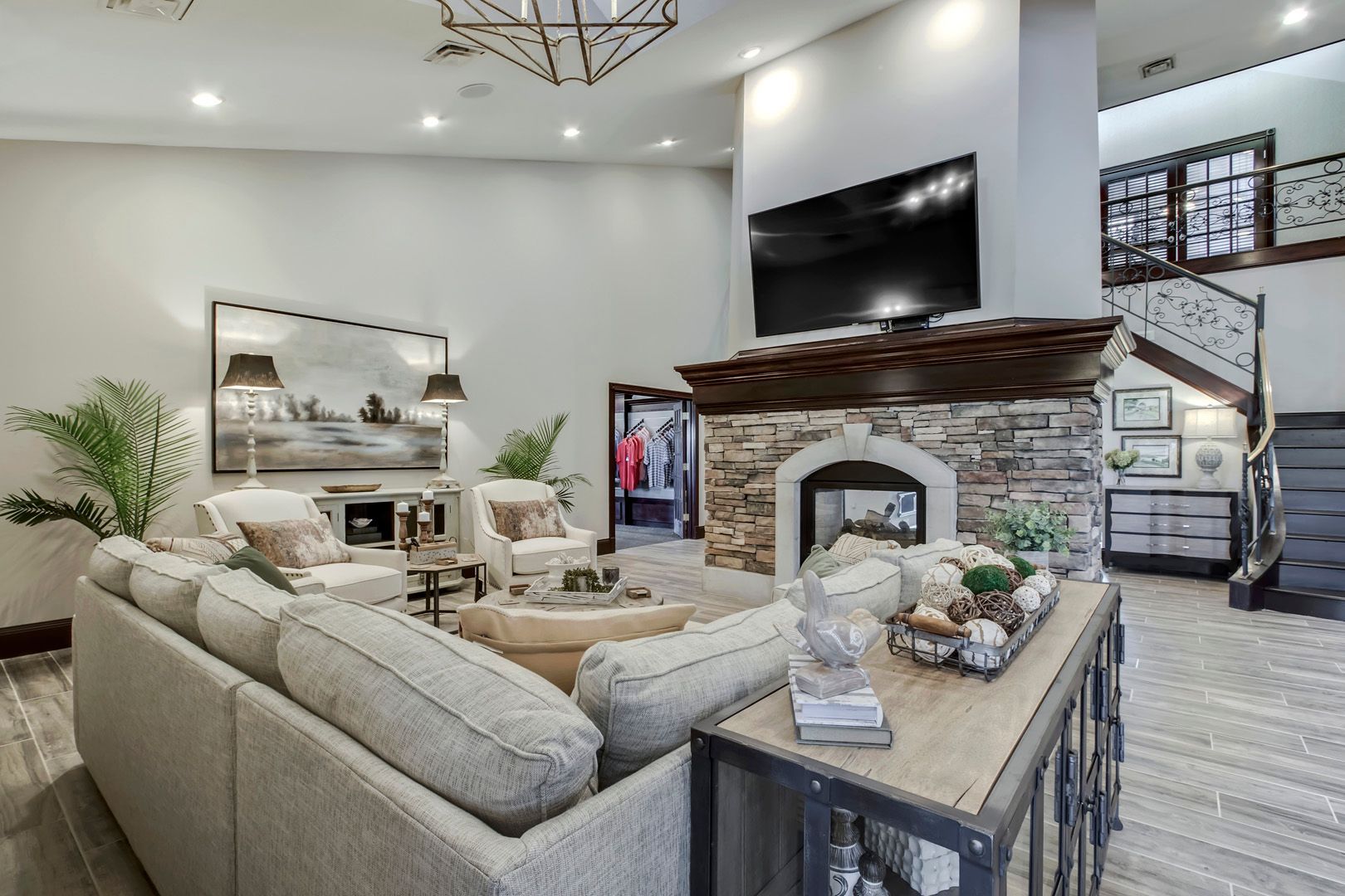 Cozy living room with fireplace, TV, sectional sofa, and staircase leading to a second floor.