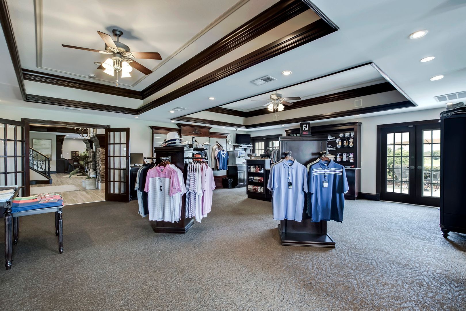 Clothing store interior, shirts on display racks, brown carpet, French doors.