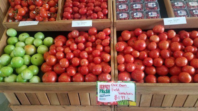 A display of tomatoes and green tomatoes with a sign that says super fresh