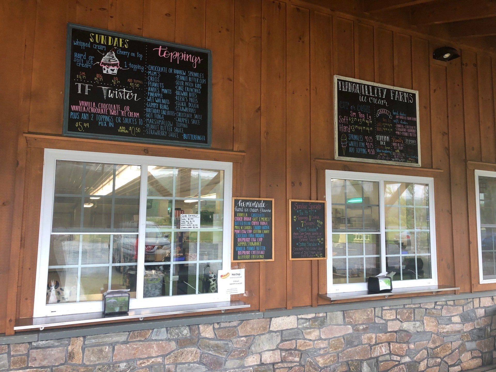 A restaurant with a wooden wall and chalkboard menus on the wall.