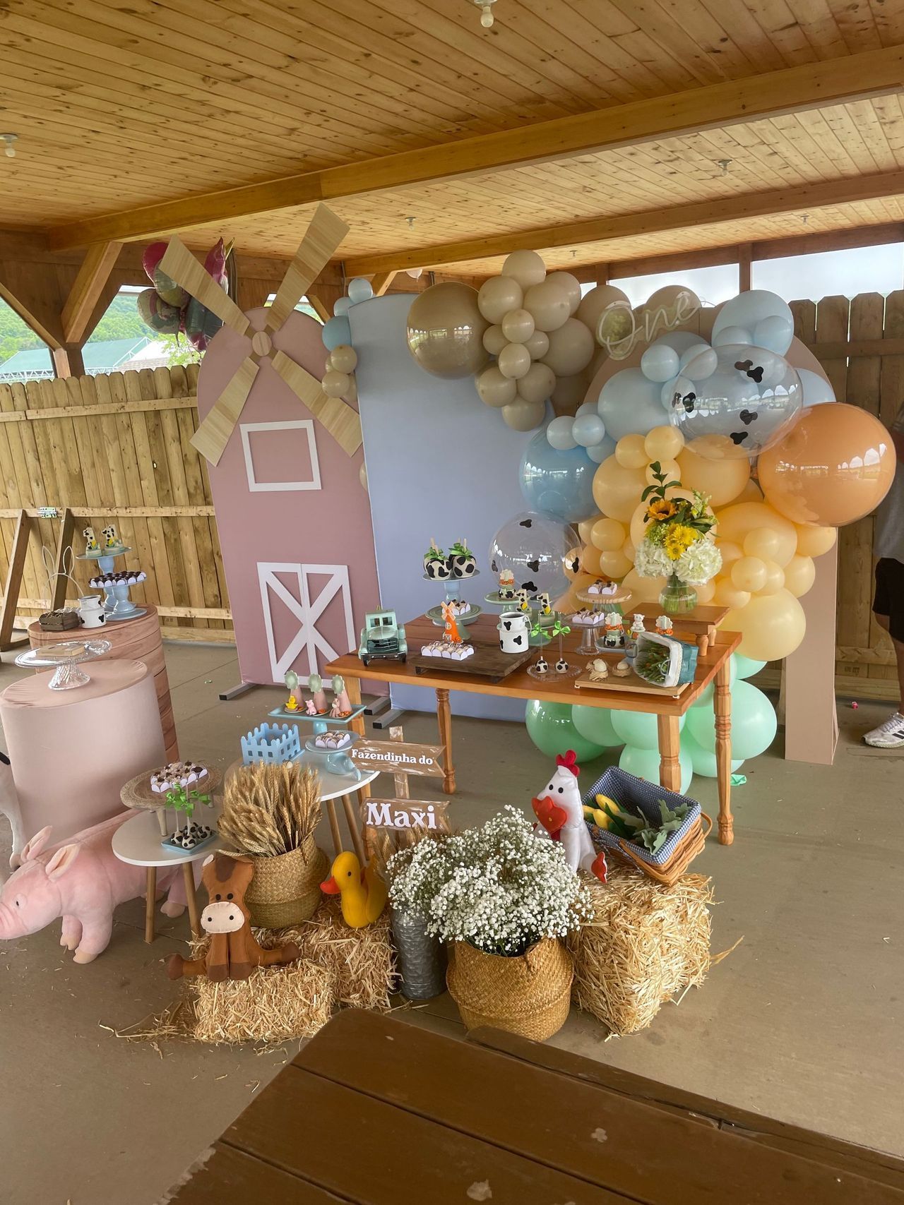 A table decorated with balloons and hay bales for a farm themed birthday party.