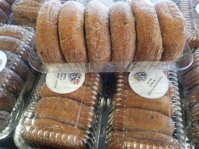 A bunch of donuts are in plastic containers on a table.