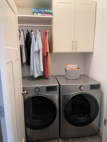 A laundry room with two washing machines and a closet filled with clothes.