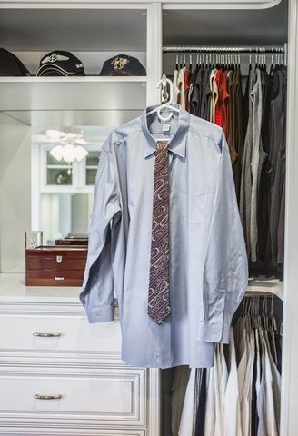 A shirt and tie are hanging in a closet.