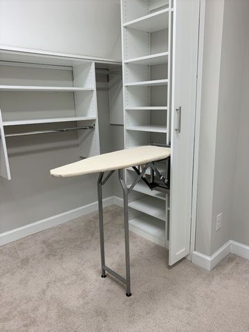 A closet with a folding ironing board inside of it.