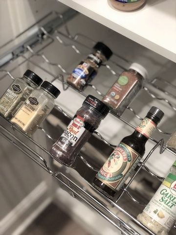 A drawer filled with bottles of spices and condiments.