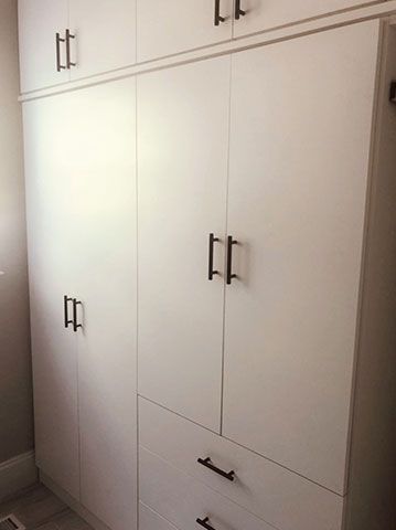 A large white cabinet with drawers and doors in a room.