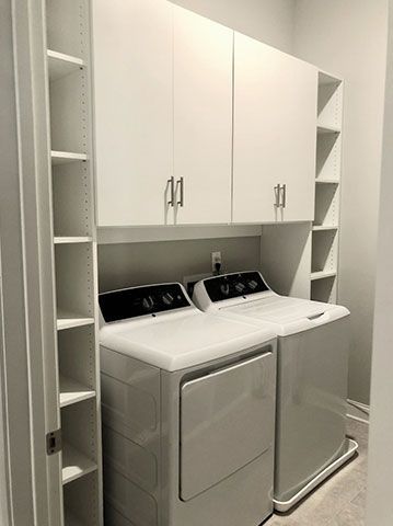 A laundry room with a washer and dryer and shelves.