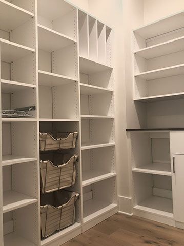 A walk in pantry with lots of shelves and baskets.