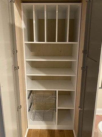 A closet with lots of shelves and a basket in it.