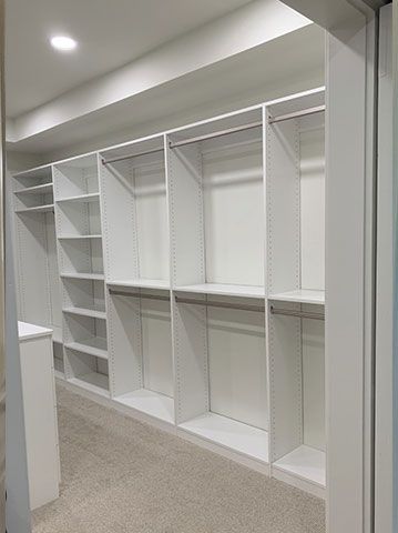 A walk in closet with lots of shelves and clothes racks.