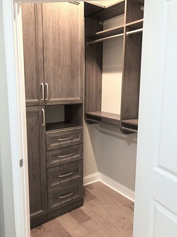 A walk in closet with wooden cabinets and drawers.