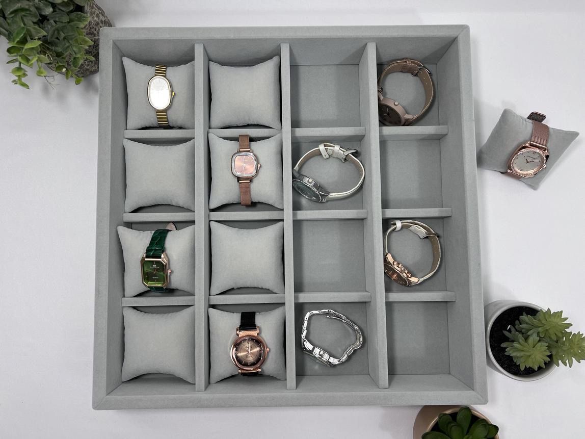 A tray filled with watches and bracelets on a table.