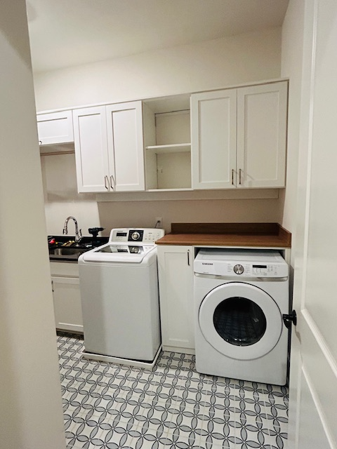 A laundry room with a washer and dryer and white cabinets.