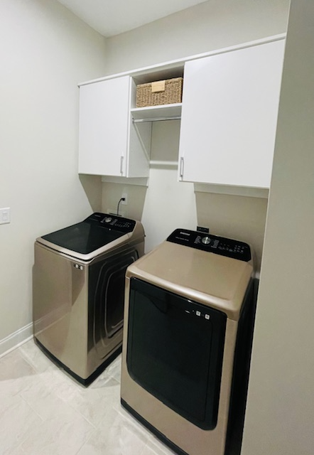 A laundry room with two washing machines and a dryer