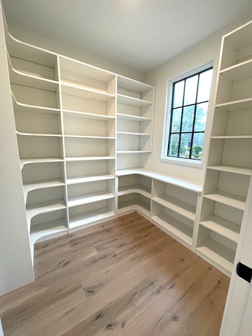 A walk in closet with lots of shelves and a window.