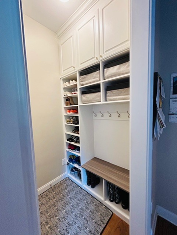 A walk in closet with lots of shelves and a bench.