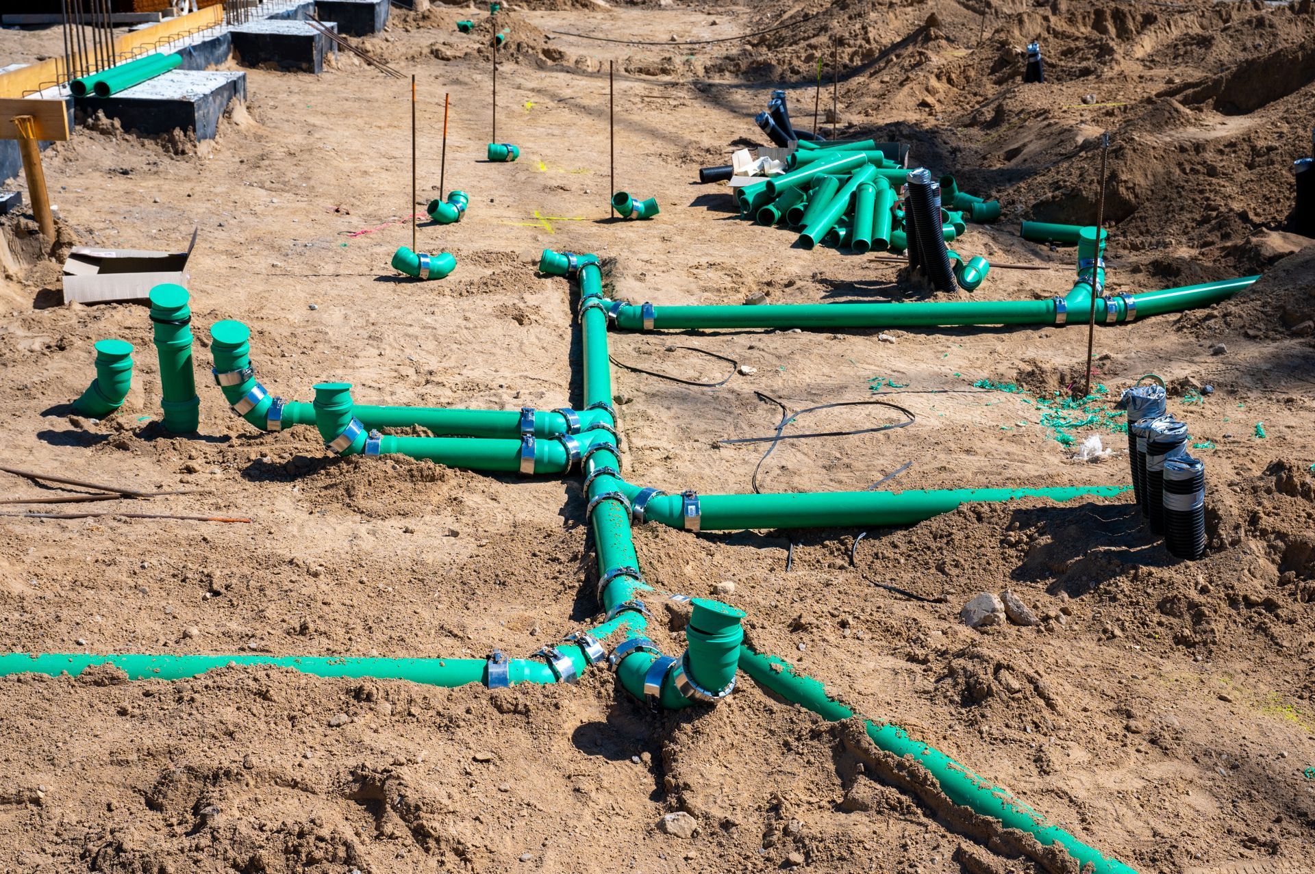 Green pipes and fittings on a sandy ground, likely a septic system installation.