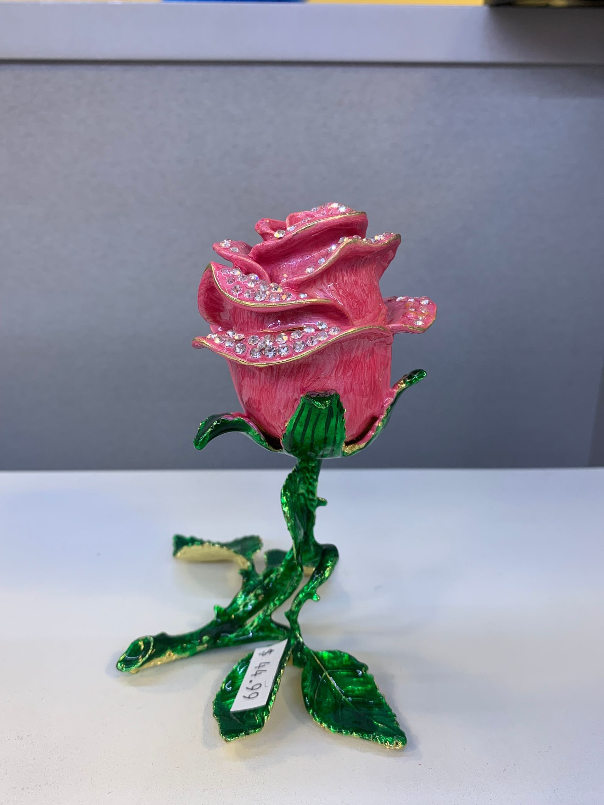 A pink rose with green leaves is on a table