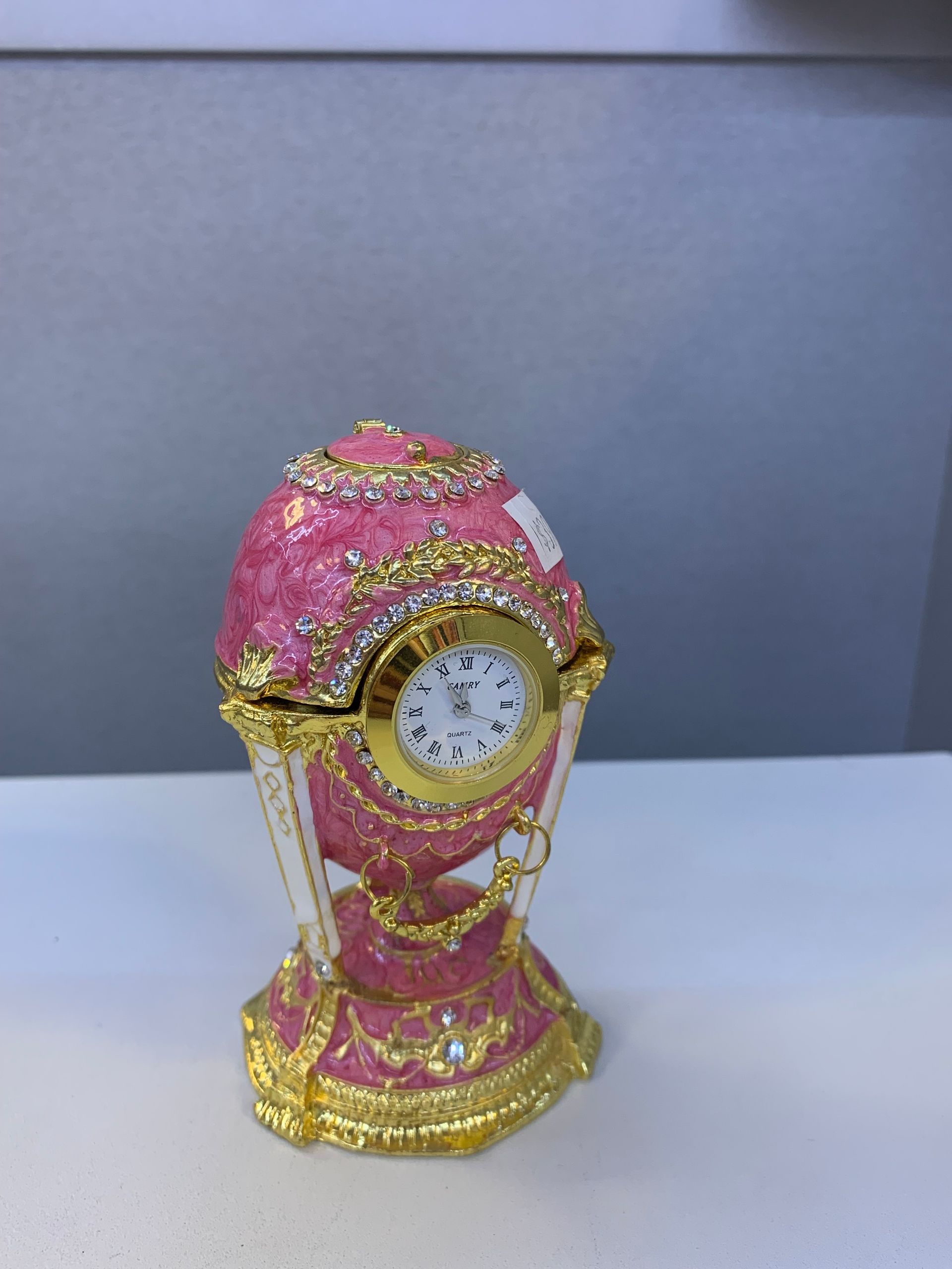 A pink and gold clock on a white table