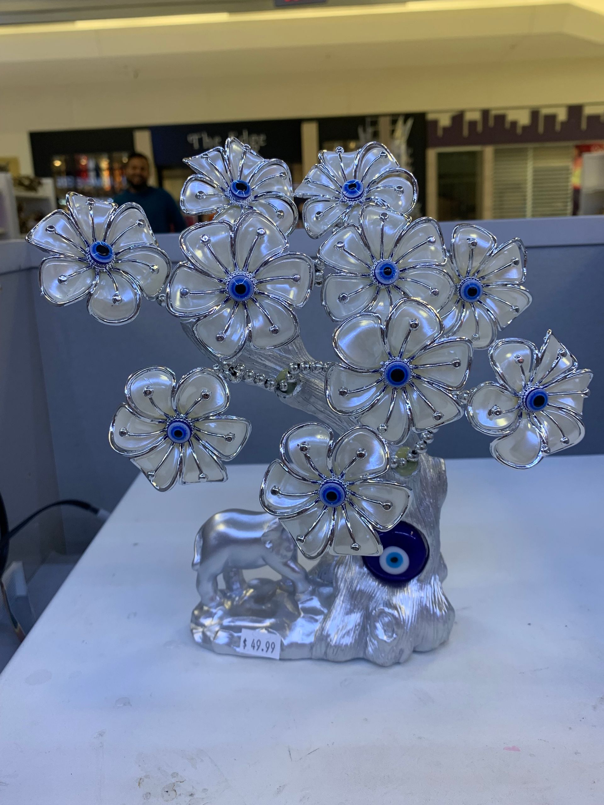 A statue of a tree with flowers and an evil eye on it