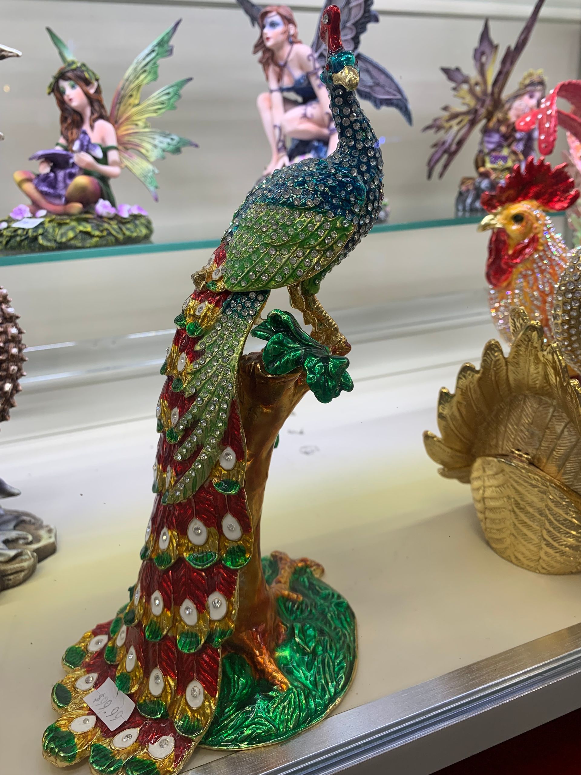 A statue of a peacock sitting on a tree branch