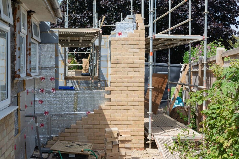 Scaffolding Around a Brick House Exterior Under Renovation, With a Narrow Walkway — Greg Pollard Building in Kingscliff, NSW