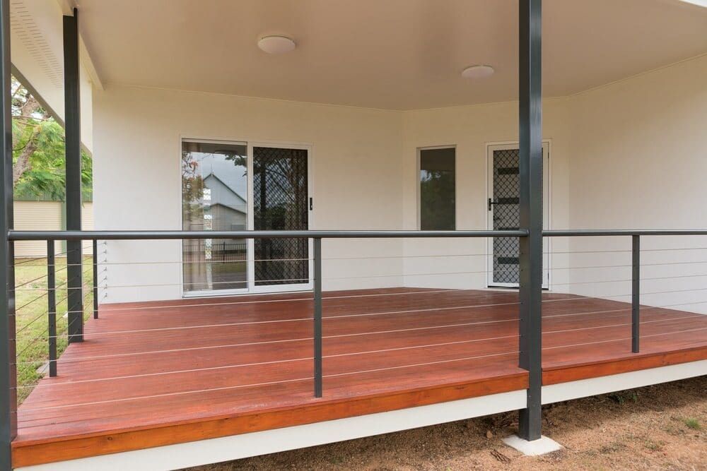 Covered Wooden Porch With Black Railings and White Columns Outside a Home — Greg Pollard Building in Bogangar, NSW