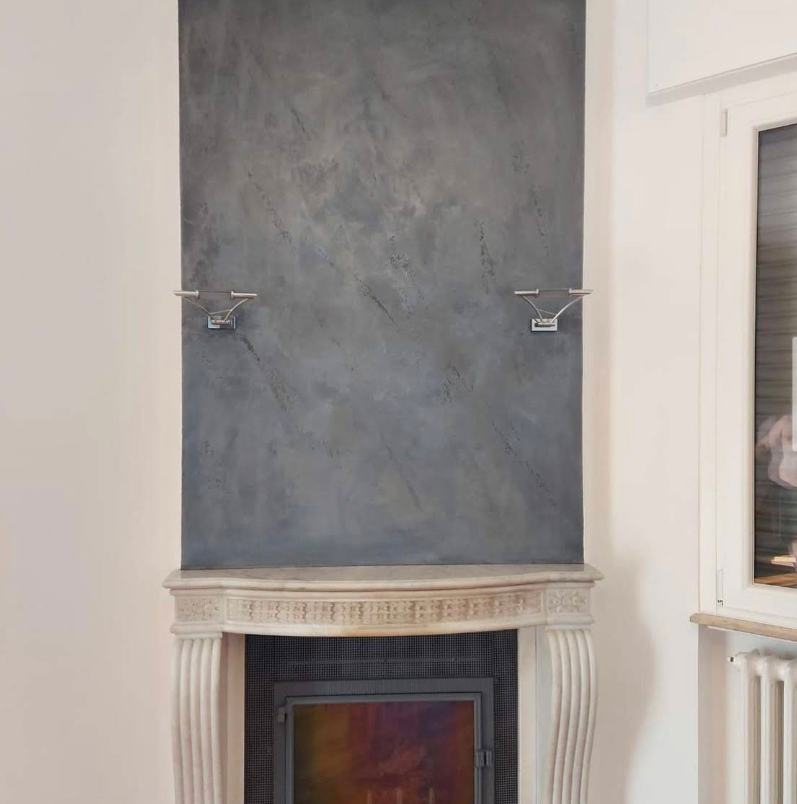 Camino con parete grigia testurizzata e mensola bianca decorata.