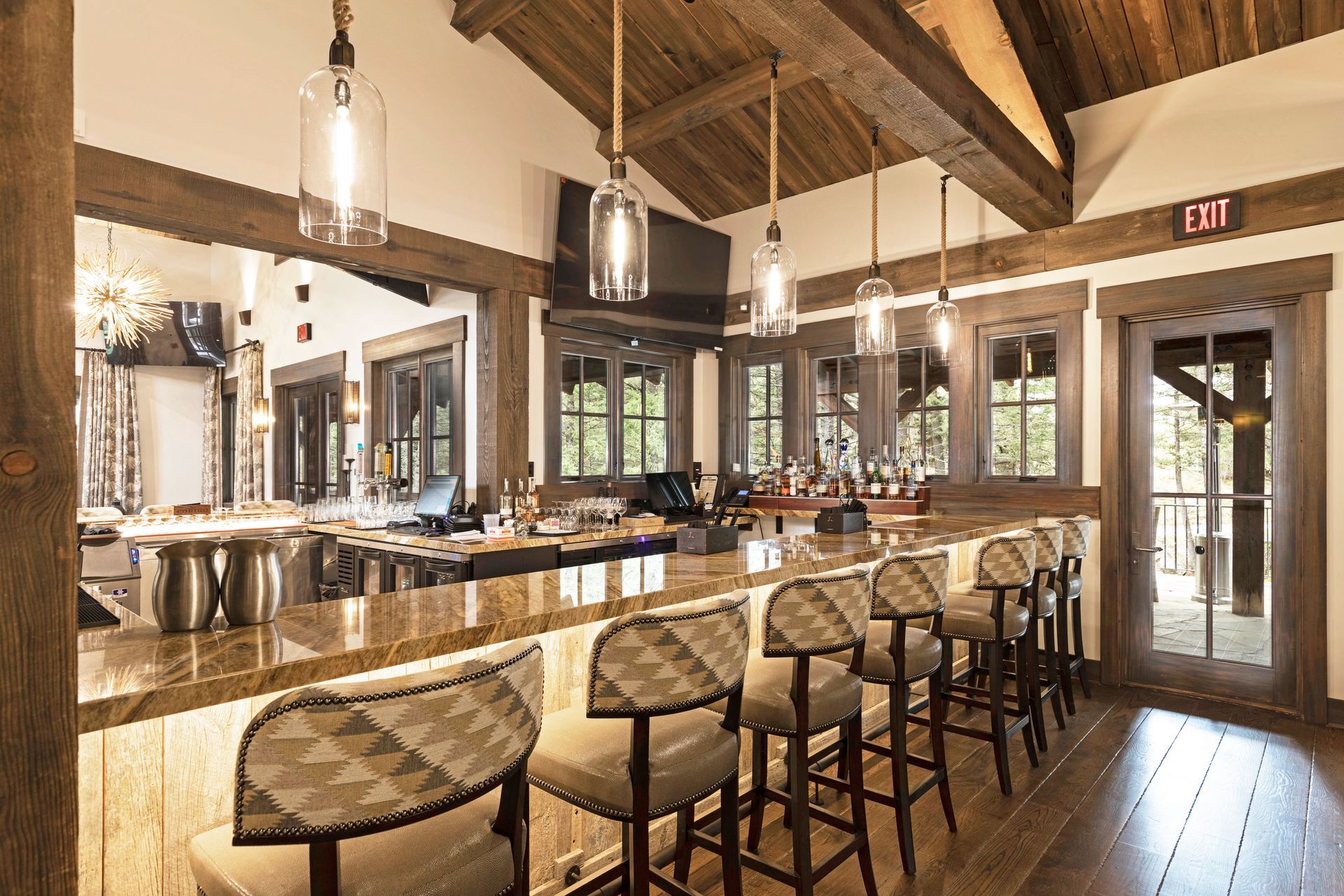 A long bar with stools in a restaurant with a wooden ceiling.