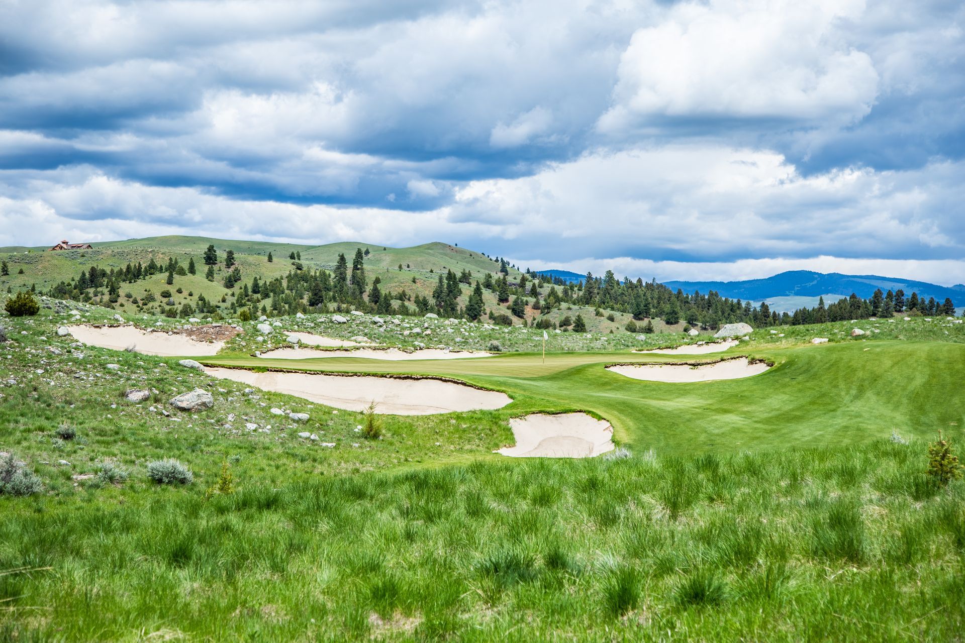 A golf course in the middle of a grassy field with mountains in the background.