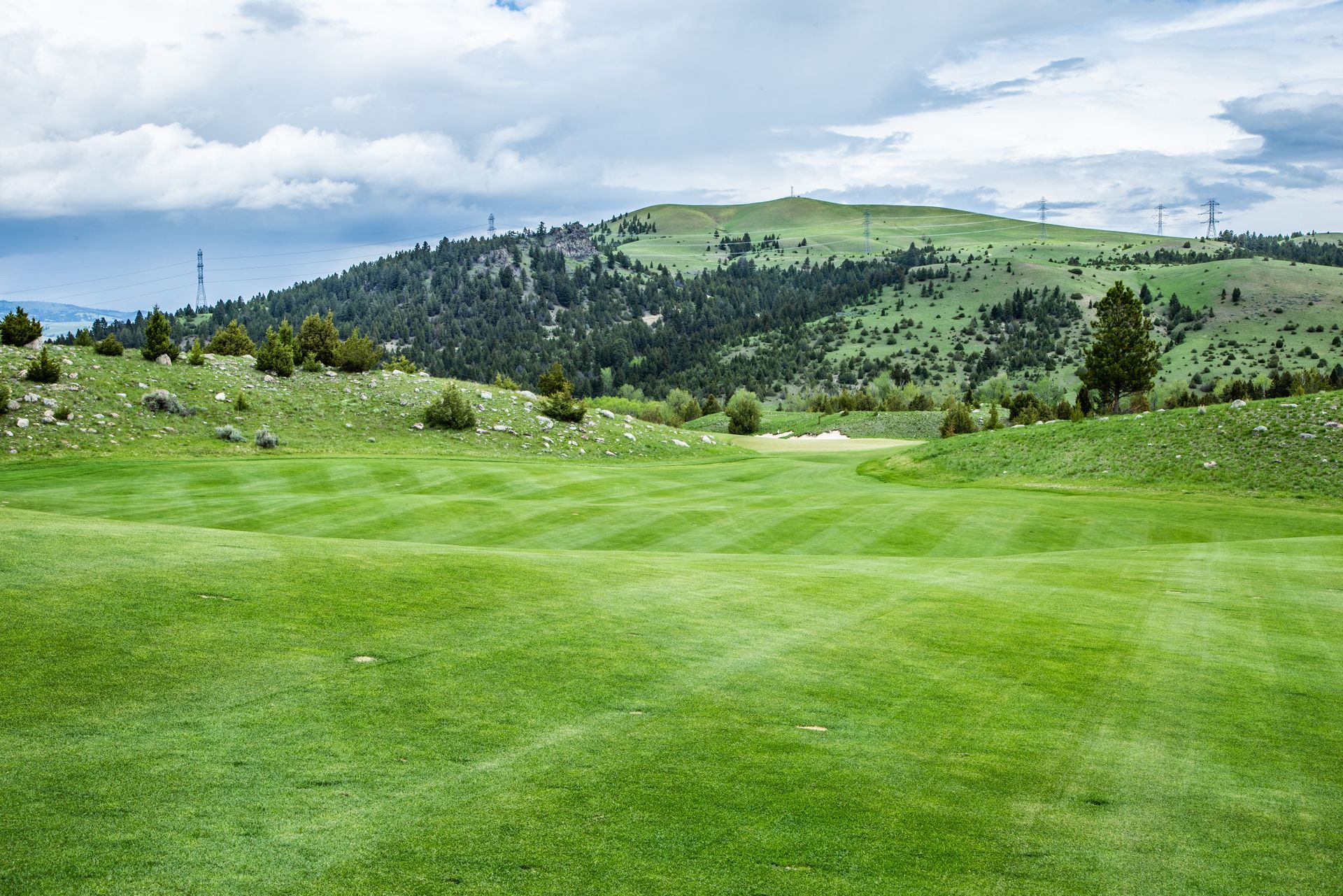 A golf course with a mountain in the background and a lush green field.