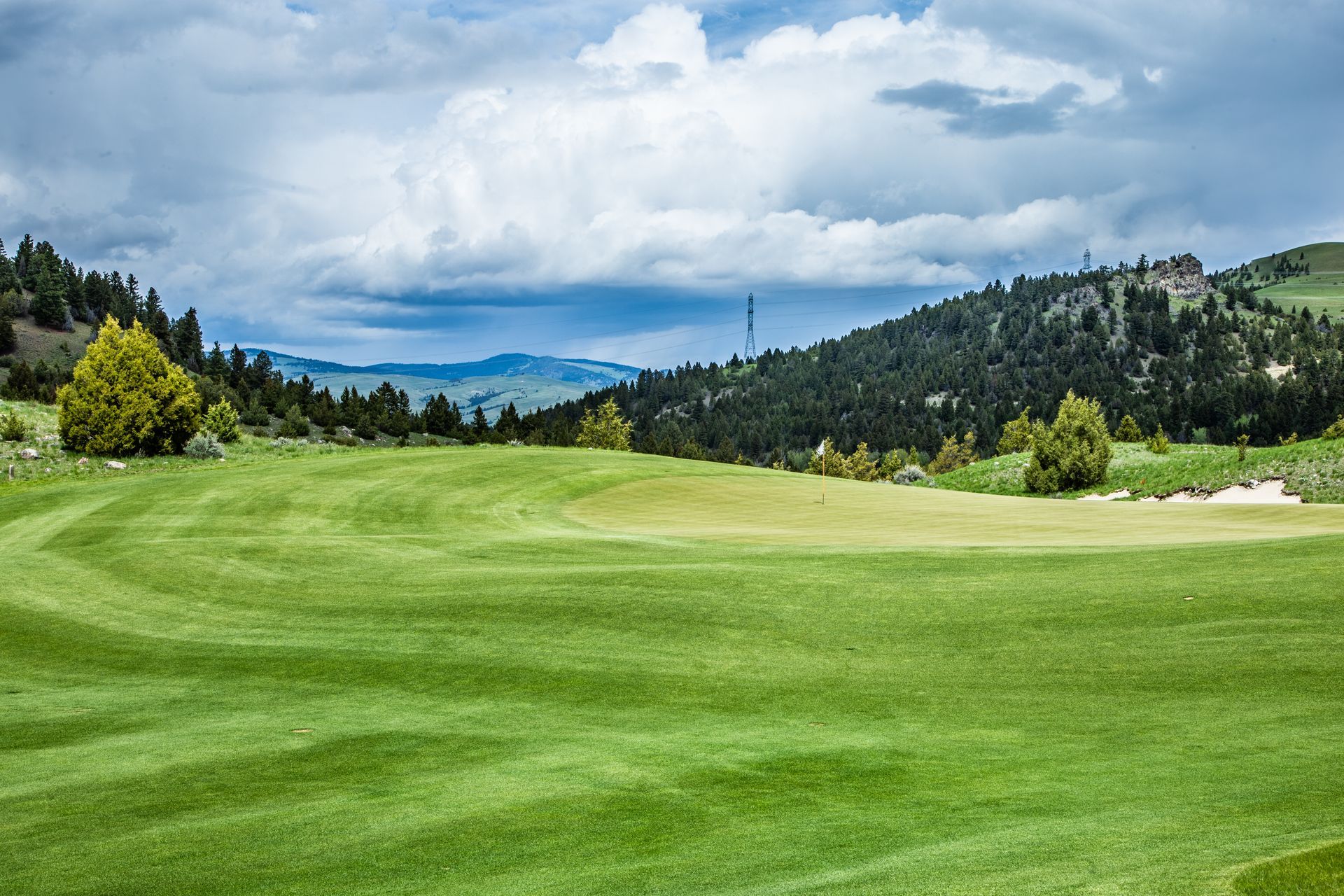 A golf course with a lot of green grass and mountains in the background.