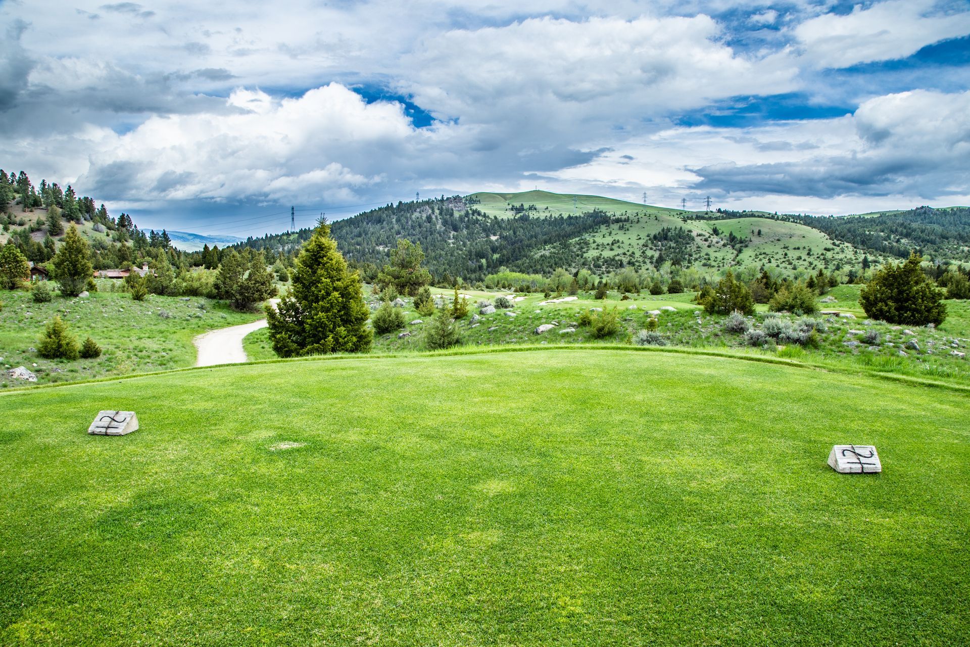A golf course in the middle of a grassy field with mountains in the background.