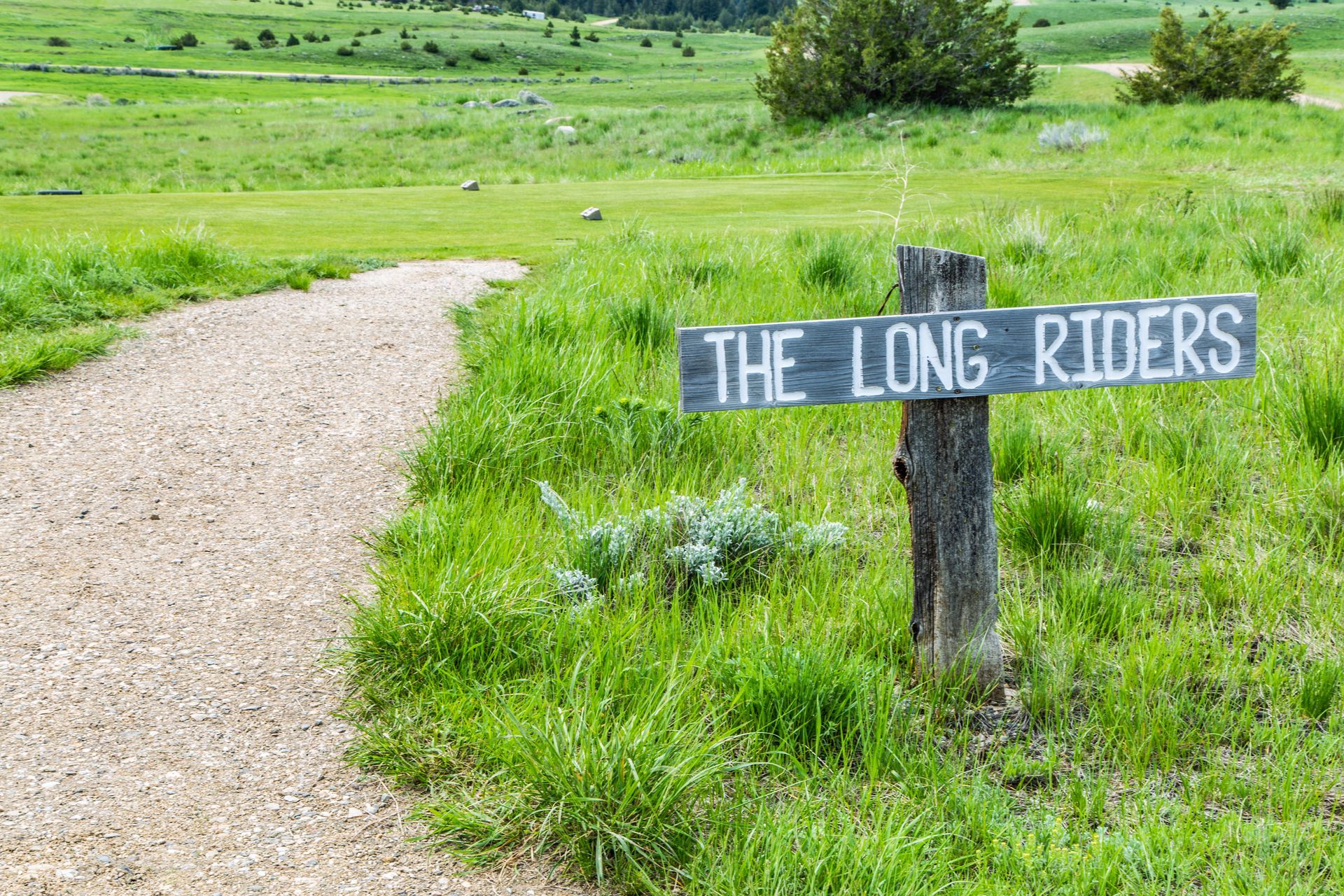 A wooden sign on the side of a dirt path says the long riders.