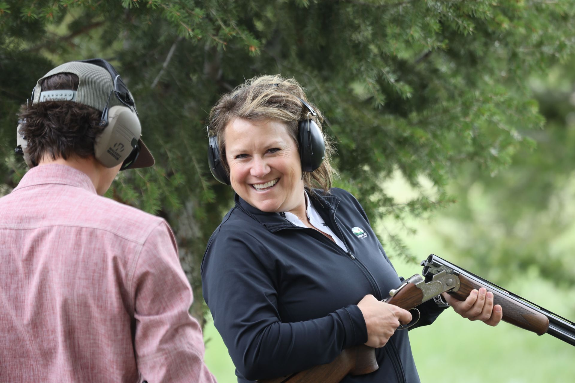 A woman is smiling while holding a shotgun