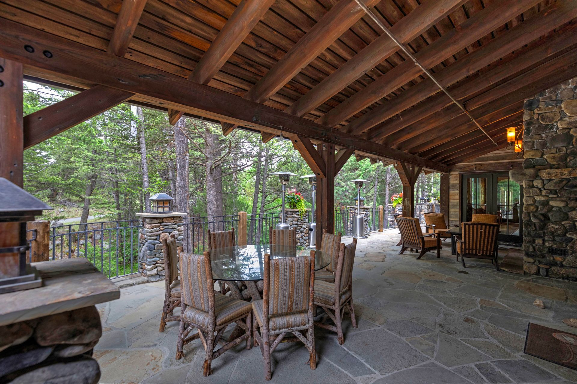 A patio with a table and chairs under a wooden roof.