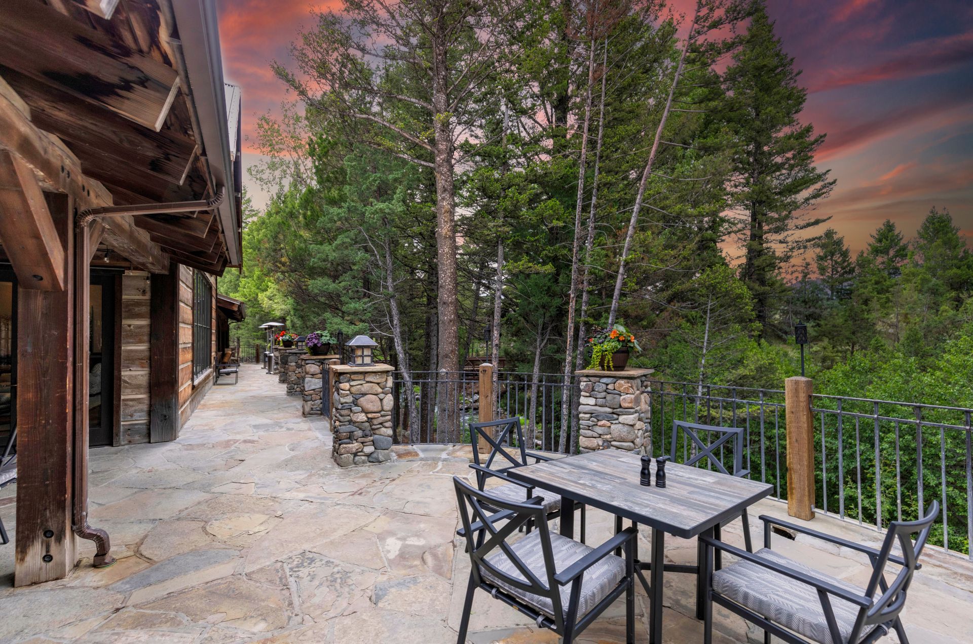 A patio with a table and chairs in the middle of a forest.