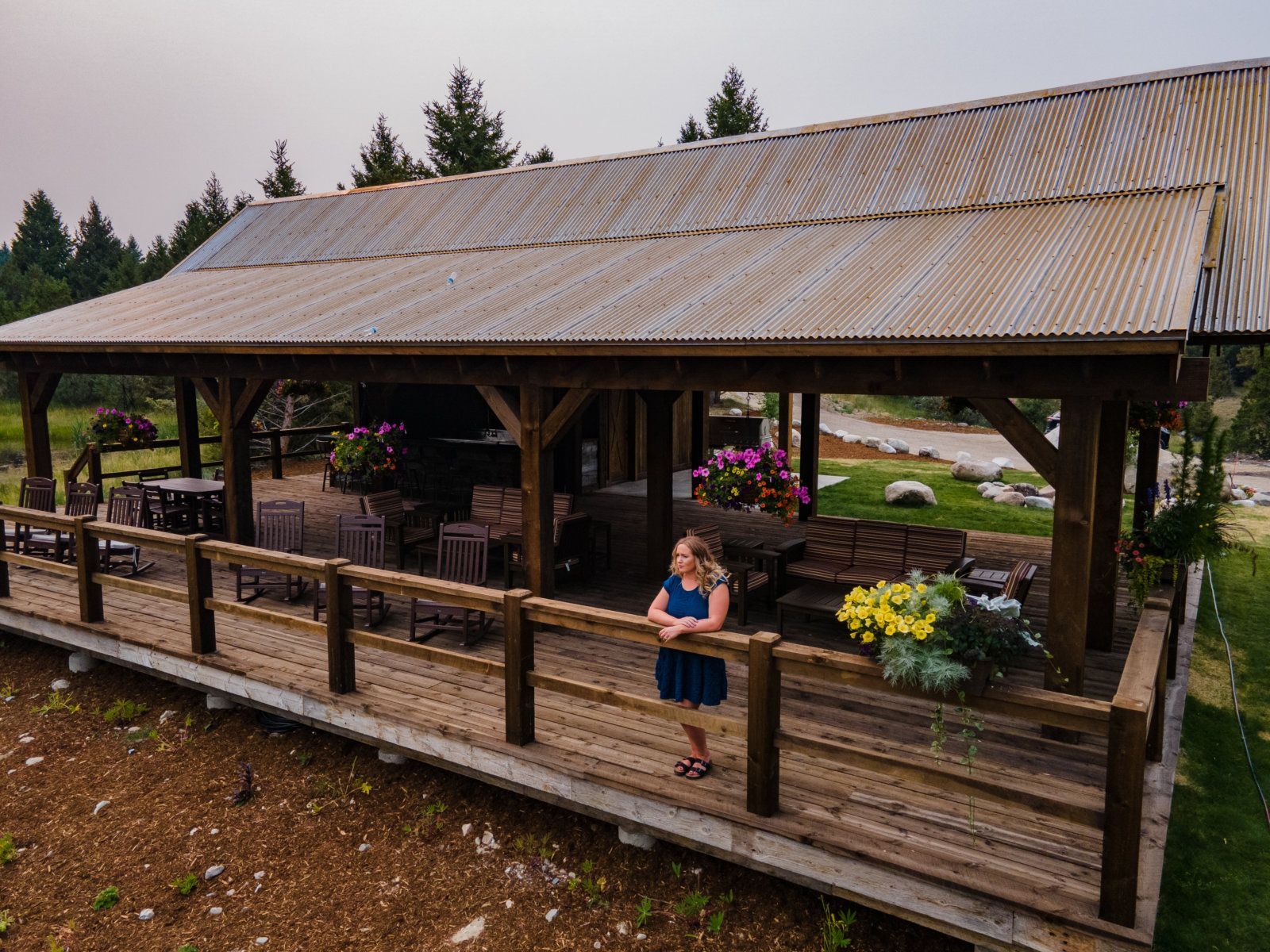 A woman is standing on a wooden deck in front of a pavilion.