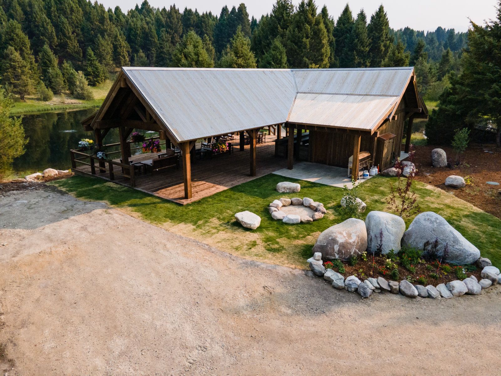 An aerial view of a pavilion with a fire pit and a lake in the background.