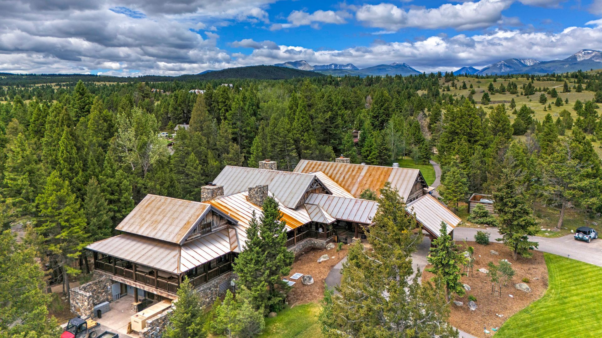 An aerial view of a large house surrounded by trees and mountains.