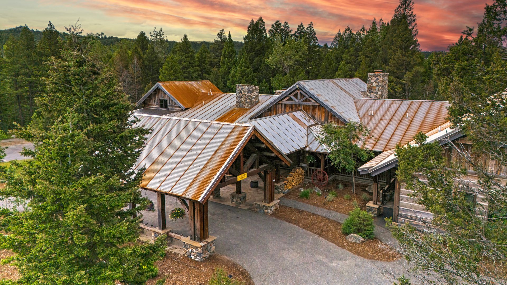 An aerial view of a large house in the middle of a forest.