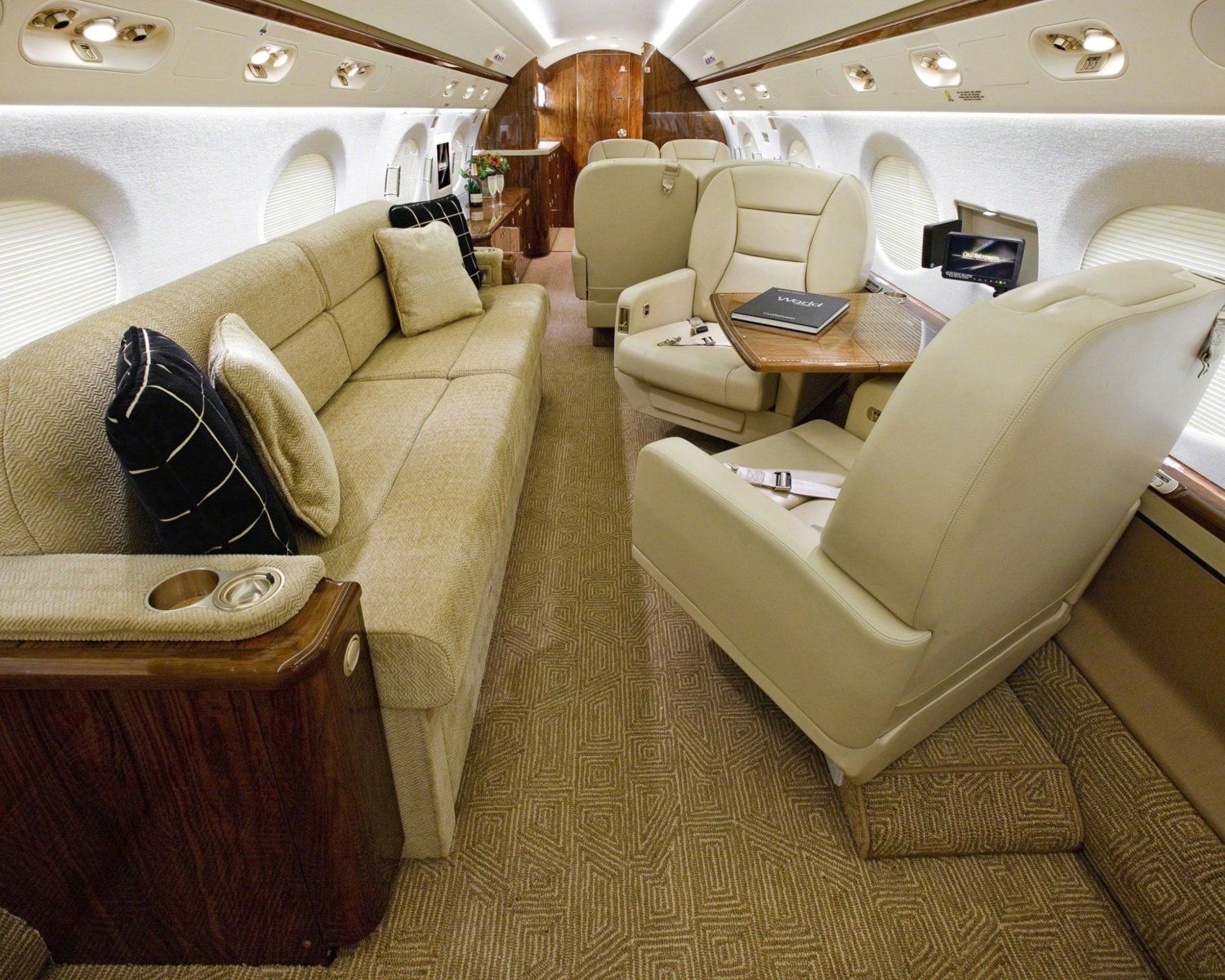The inside of a private jet with a couch and chairs