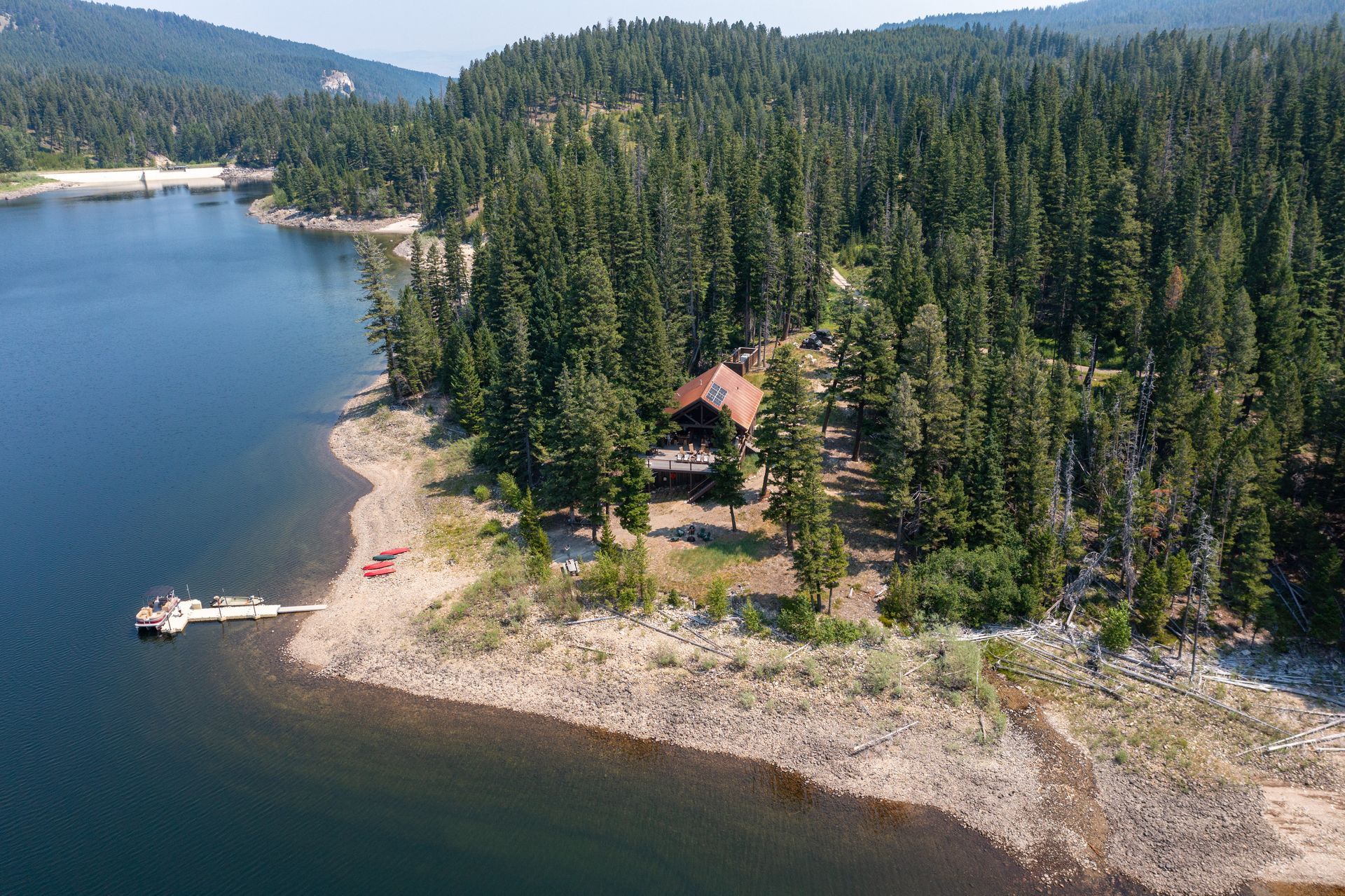 An aerial view of a lake surrounded by trees and mountains.
