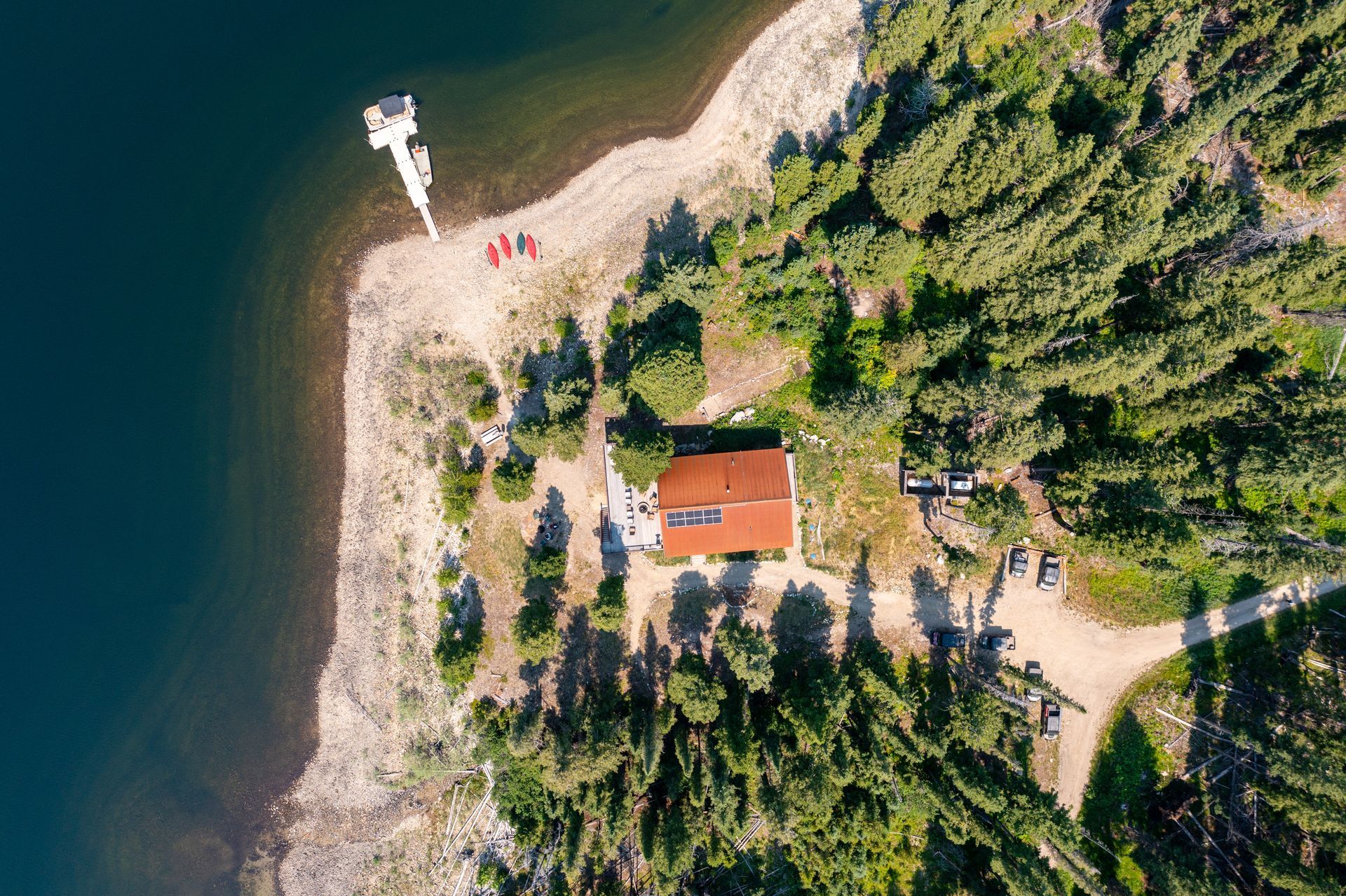 An aerial view of a house on a small island in the middle of a lake surrounded by trees.