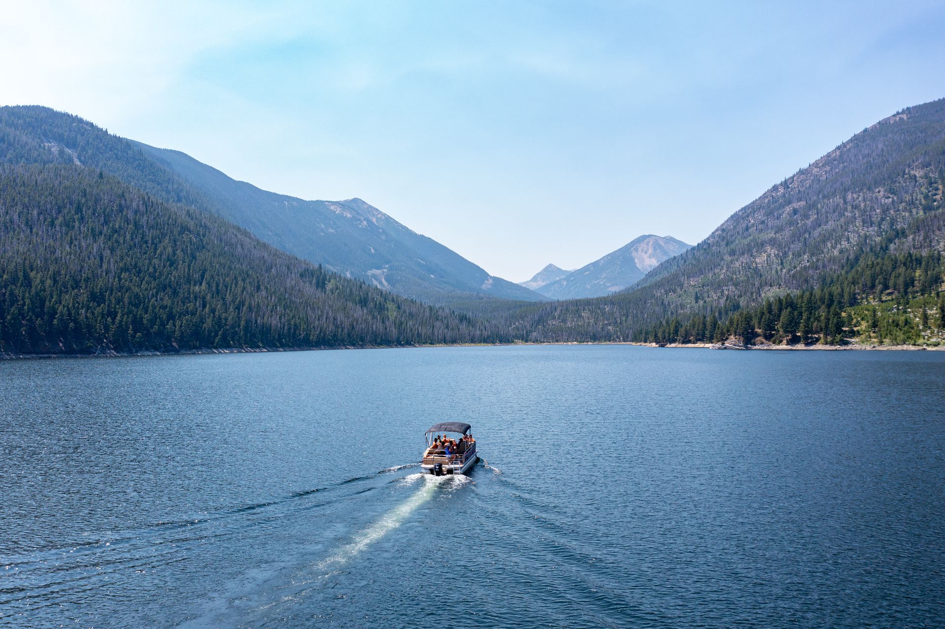 A boat is floating on a lake with mountains in the background.